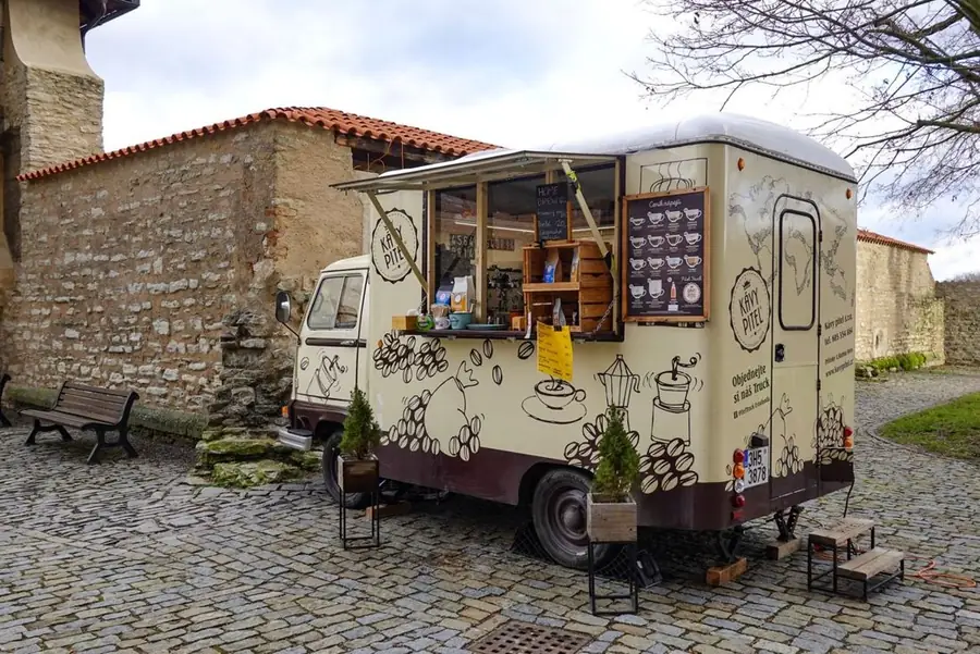 Mobiles Café in einem umgebauten Wohnwagen auf einem Platz mit Kopfsteinpflaster
