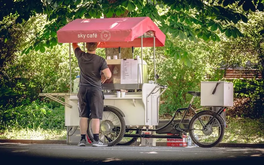 Mobiler Kaffeewagen mit rotem Schirm im Park